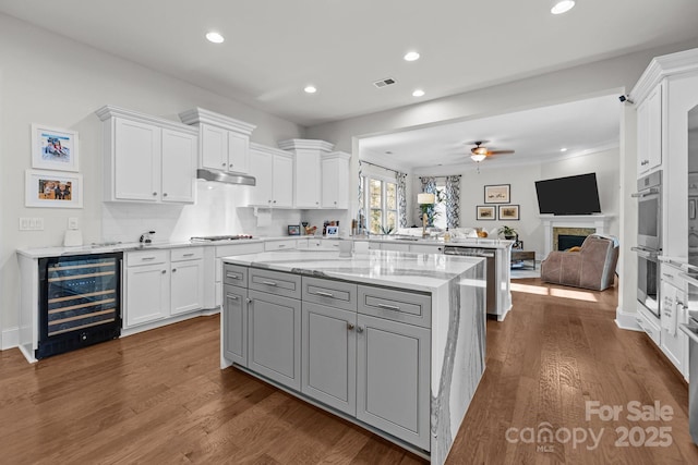 16522 Flintrock Falls Ln, Charlotte, NC 28278 - kitchen with beverage cooler, a peninsula, open floor plan, white cabinetry, and ceiling fan