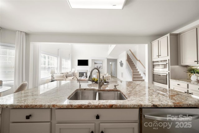 14801 Provence Ln, Charlotte, NC 28277 - kitchen with appliances with stainless steel finishes, open floor plan, a kitchen island with sink, light stone countertops, and a fireplace