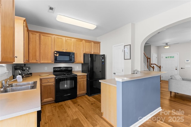 514 Bent Leaf Ct, Fort Mill, SC 29708 - kitchen with black appliances, light wood-style flooring, light countertops, arched walkways, and open floor plan