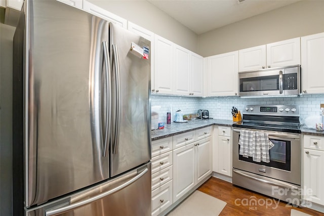 11521 Savannah Creek Dr, Charlotte, NC 28273 - kitchen featuring stainless steel appliances, white cabinetry, decorative backsplash, dark stone countertops, and dark wood-style flooring