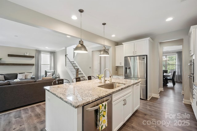 10437 Paper Birch Dr, Charlotte, NC 28215 - kitchen with stainless steel appliances, an island with sink, open floor plan, white cabinets, and light stone countertops