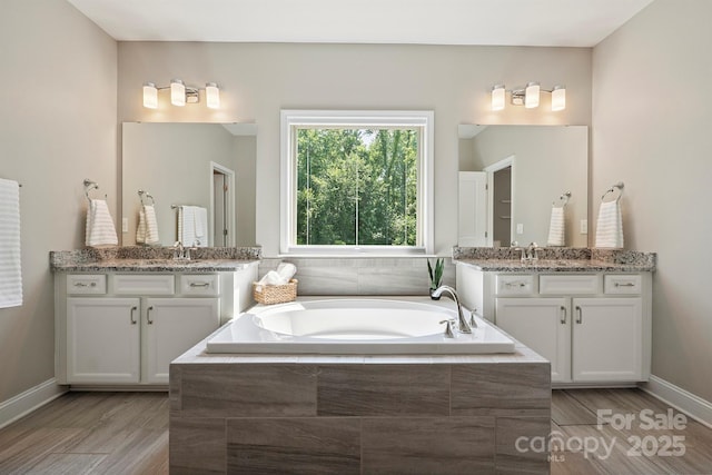 10437 Paper Birch Dr, Charlotte, NC 28215 - full bath featuring a garden tub, two vanities, and wood finished floors