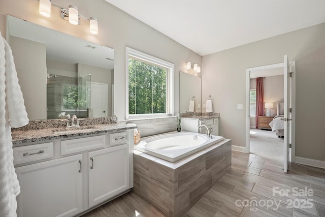 10437 Paper Birch Dr, Charlotte, NC 28215 - ensuite bathroom featuring vanity, a bath, a tile shower, and wood finished floors