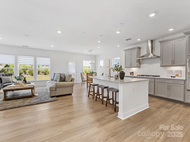 1516 Respect St NW, Concord, NC 28027 - kitchen with wall chimney range hood, open floor plan, gray cabinets, a breakfast bar, and an island with sink