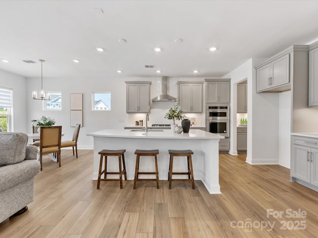 1516 Respect St NW, Concord, NC 28027 - kitchen with gray cabinetry, wall chimney exhaust hood, open floor plan, a breakfast bar area, and a chandelier
