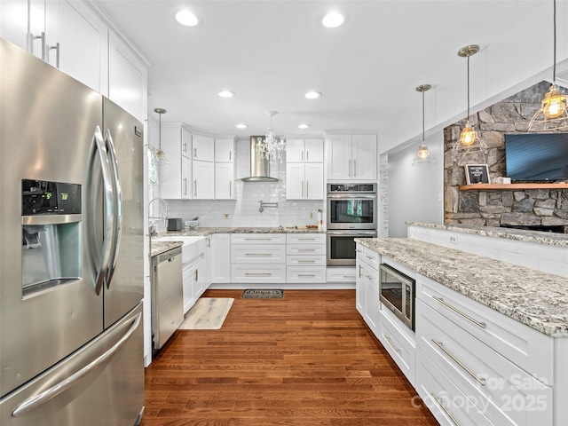 220 Deer Run Rd, Canton, NC 28716 - kitchen featuring appliances with stainless steel finishes, wall chimney range hood, dark wood-type flooring, white cabinetry, and decorative backsplash