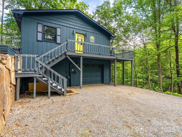 220 Deer Run Rd, Canton, NC 28716 - chalet / cabin featuring gravel driveway, an attached garage, a wooden deck, board and batten siding, and stairs