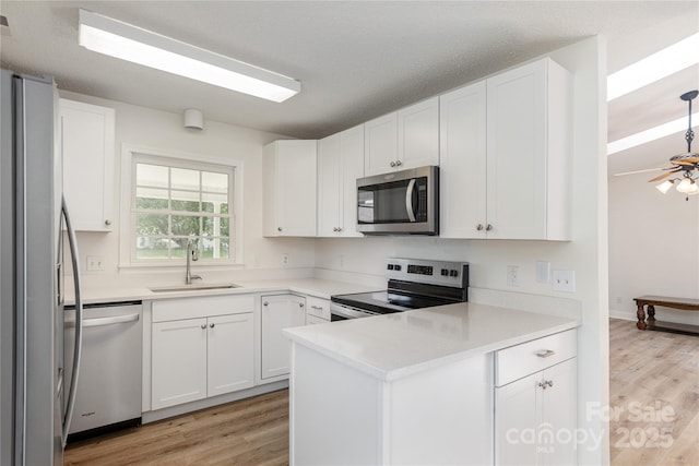 802 Woodlark Ct, Fletcher, NC 28732 - kitchen with stainless steel appliances, light wood-style floors, white cabinetry, and a peninsula
