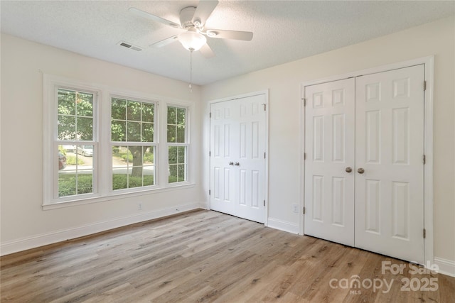 802 Woodlark Ct, Fletcher, NC 28732 - unfurnished bedroom featuring two closets, wood finished floors, a textured ceiling, and a ceiling fan