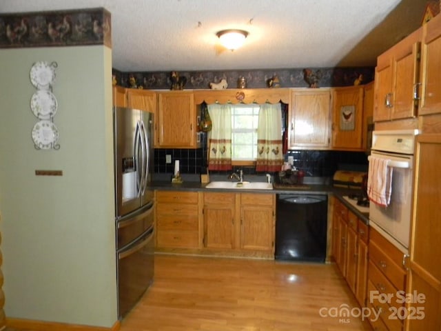 1425 Sorrells Cove Rd, Clyde, NC 28721 - kitchen featuring stainless steel fridge, dishwasher, oven, dark countertops, and light wood-style flooring
