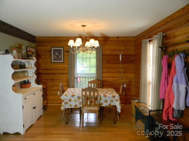 1425 Sorrells Cove Rd, Clyde, NC 28721 - dining space featuring log walls, a chandelier, and light wood-style flooring