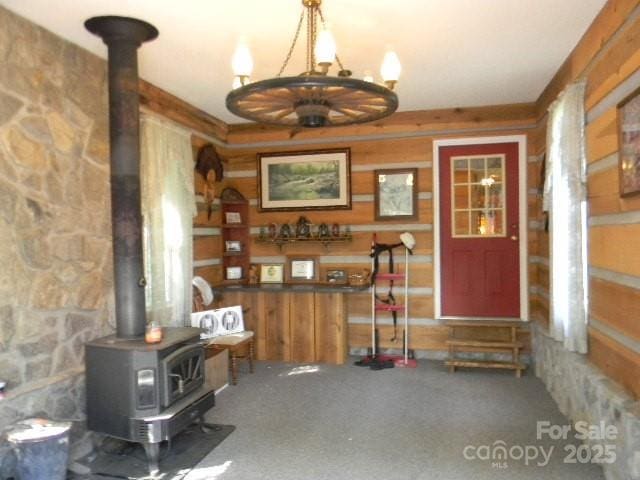 1425 Sorrells Cove Rd, Clyde, NC 28721 - entrance foyer with a wood stove, wood walls, carpet, and a chandelier