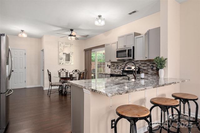 6422 Gatesville Ln, Charlotte, NC 28270 - kitchen featuring appliances with stainless steel finishes, a peninsula, ceiling fan, light stone counters, and backsplash