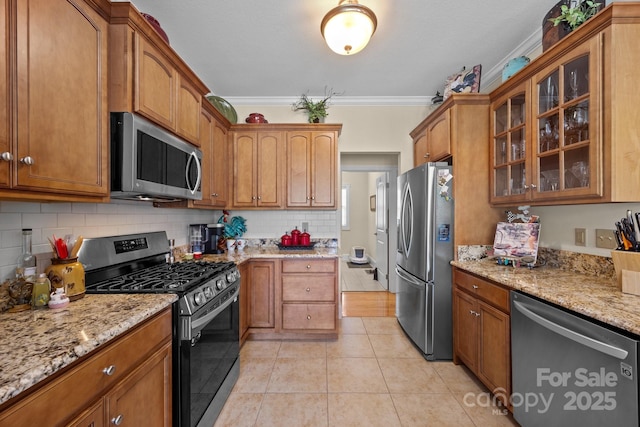 1006 Pin Oak Trl Unit 5, Hendersonville, NC 28739 - kitchen featuring appliances with stainless steel finishes, light tile patterned flooring, tasteful backsplash, brown cabinets, and ornamental molding