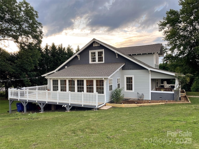 102 Cuthberson St, Morganton, NC 28655 - back of property at dusk with a shingled roof, a lawn, a deck, and a sunroom