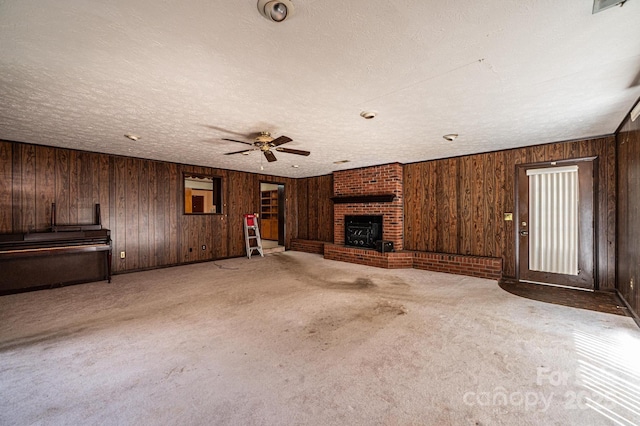 3954 E Burke Blvd, Connelly Springs, NC 28612 - unfurnished living room featuring a ceiling fan, a brick fireplace, wooden walls, carpet flooring, and a textured ceiling