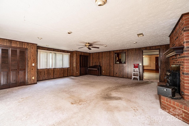 3954 E Burke Blvd, Connelly Springs, NC 28612 - unfurnished living room featuring a ceiling fan, wood walls, carpet, a textured ceiling, and a wood stove