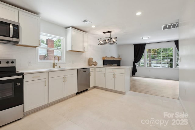 5420 Gwynne Ave, Charlotte, NC 28205 - kitchen featuring appliances with stainless steel finishes, light countertops, a peninsula, tasteful backsplash, and white cabinetry