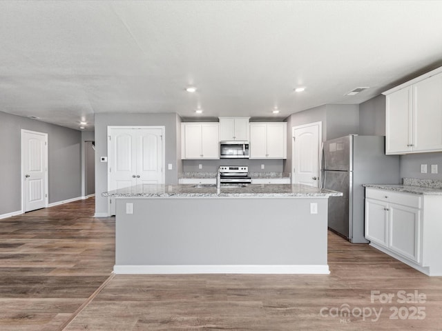 9136 Creedmore Hills Dr, Charlotte, NC 28214 - kitchen featuring stainless steel appliances, a kitchen island with sink, white cabinets, wood finished floors, and recessed lighting
