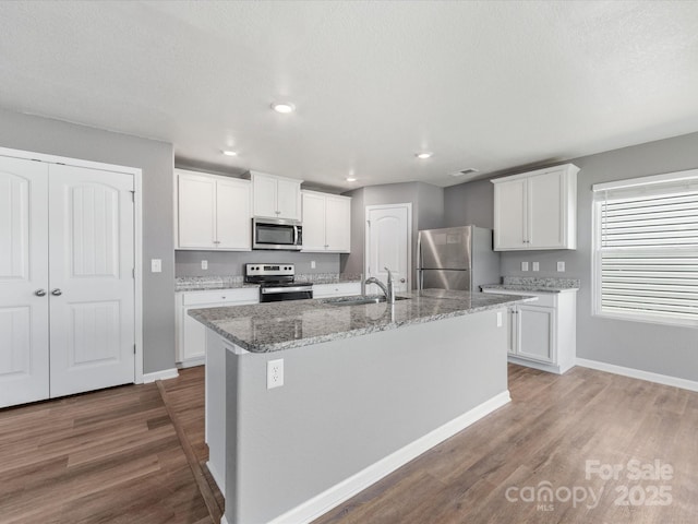 9136 Creedmore Hills Dr, Charlotte, NC 28214 - kitchen featuring stainless steel appliances, wood finished floors, an island with sink, white cabinetry, and recessed lighting