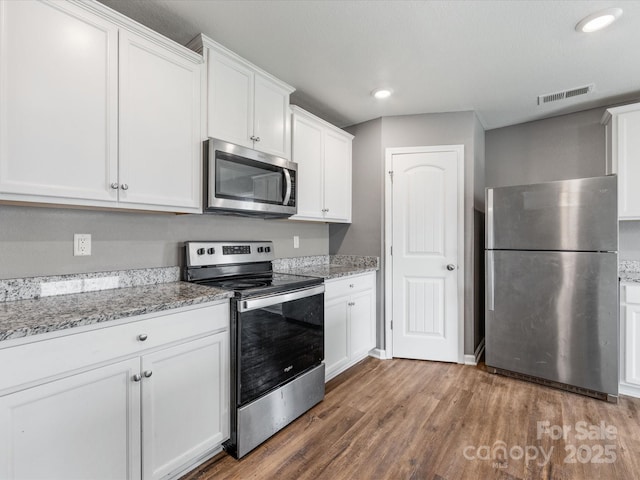 9136 Creedmore Hills Dr, Charlotte, NC 28214 - kitchen featuring appliances with stainless steel finishes, light wood-type flooring, white cabinets, and recessed lighting