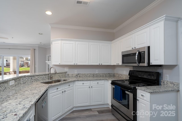 18511 Harborside Dr, Cornelius, NC 28031 - kitchen featuring stainless steel appliances, white cabinets, light stone counters, light wood-style floors, and ornamental molding