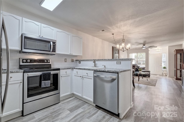 1504 Harpers Inlet Dr, Lake Wylie, SC 29710 - kitchen featuring appliances with stainless steel finishes, white cabinets, a peninsula, tasteful backsplash, and a textured ceiling