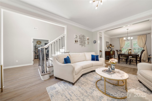 1125 Victoria Blake Ln, Belmont, NC 28012 - living room featuring light wood-style floors, stairs, a chandelier, ornamental molding, and decorative columns