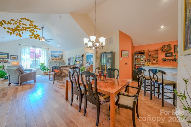 38 Westfield Way, Candler, NC 28715 - dining area with lofted ceiling, light wood finished floors, a chandelier, a fireplace, and a ceiling fan