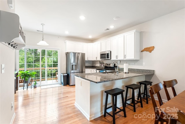 6507 Revolutionary Trl, Charlotte, NC 28217 - kitchen with appliances with stainless steel finishes, a peninsula, dark stone counters, white cabinetry, and light wood finished floors