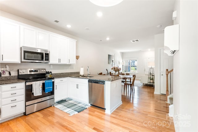 6507 Revolutionary Trl, Charlotte, NC 28217 - kitchen with stainless steel appliances, a peninsula, light wood finished floors, white cabinets, and recessed lighting