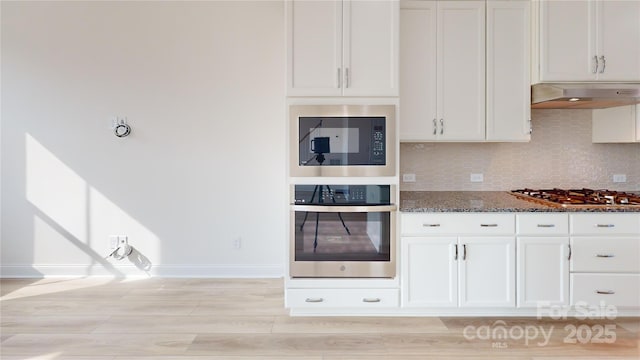 2143 Barrowcliffe Dr NW, Concord, NC 28027 - kitchen with appliances with stainless steel finishes, dark stone countertops, under cabinet range hood, and backsplash