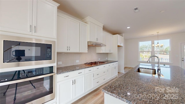 2143 Barrowcliffe Dr NW, Concord, NC 28027 - kitchen with appliances with stainless steel finishes, dark stone counters, a chandelier, decorative backsplash, and recessed lighting