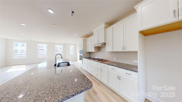 2143 Barrowcliffe Dr NW, Concord, NC 28027 - kitchen featuring under cabinet range hood, white cabinetry, tasteful backsplash, dark stone counters, and recessed lighting