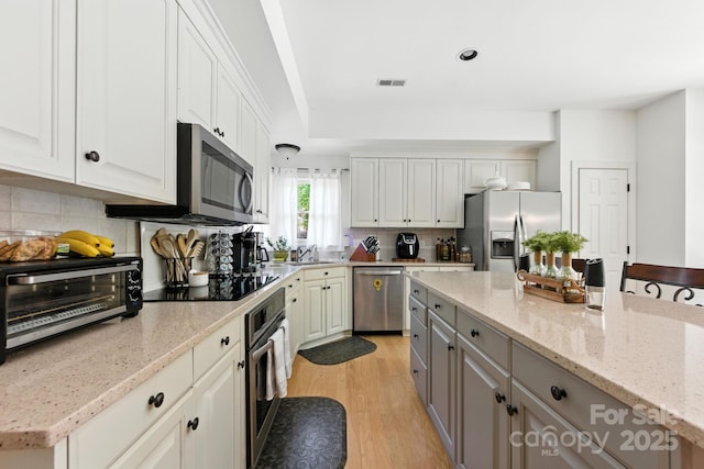 7014 Walton Heath Ln, Charlotte, NC 28277 - kitchen featuring stainless steel appliances, decorative backsplash, light wood-style flooring, light stone countertops, and gray cabinets
