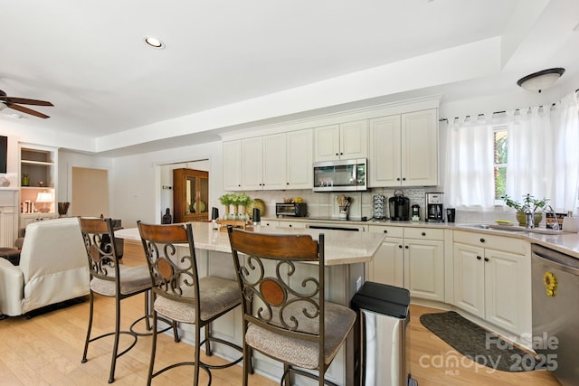 7014 Walton Heath Ln, Charlotte, NC 28277 - kitchen with appliances with stainless steel finishes, open floor plan, a kitchen bar, ceiling fan, and light wood-style floors
