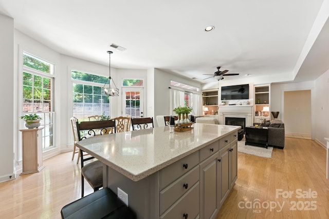 7014 Walton Heath Ln, Charlotte, NC 28277 - kitchen with a ceiling fan, a fireplace, gray cabinets, a center island, and light wood-style flooring
