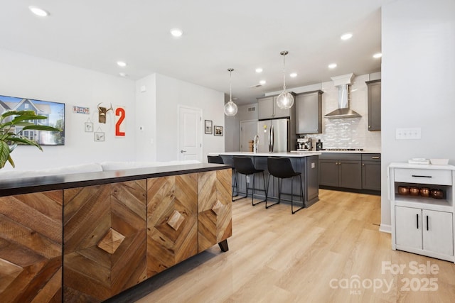 5008 Calvine Mill Way, Charlotte, NC 28205 - kitchen featuring wall chimney exhaust hood, gray cabinets, freestanding refrigerator, a kitchen bar, and cooktop