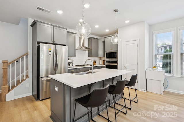 5008 Calvine Mill Way, Charlotte, NC 28205 - kitchen featuring appliances with stainless steel finishes, gray cabinets, wall chimney exhaust hood, light wood finished floors, and recessed lighting
