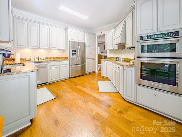 133 Sassafras Hill Dr, Rutherfordton, NC 28139 - kitchen featuring appliances with stainless steel finishes, custom exhaust hood, tasteful backsplash, light wood finished floors, and light stone counters
