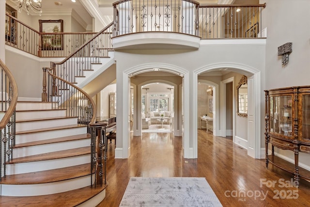 9110 Woodhall Lake Dr, Waxhaw, NC 28173 - foyer entrance featuring a towering ceiling, arched walkways, crown molding, stairway, and wood finished floors