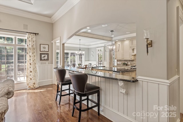 9110 Woodhall Lake Dr, Waxhaw, NC 28173 - kitchen with a kitchen bar, wood finished floors, arched walkways, a chandelier, and cream cabinets