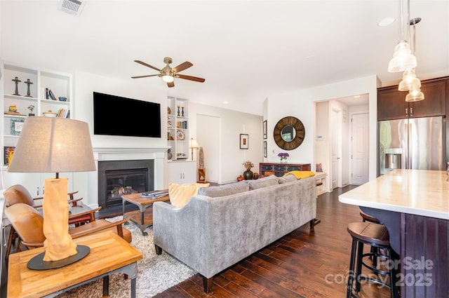 11225 Black Brant Ln, Charlotte, NC 28278 - living room featuring a ceiling fan, dark wood-style flooring, a glass covered fireplace, built in shelves, and recessed lighting