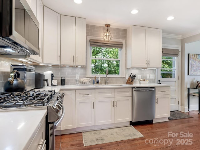 4618 Emory Ln, Charlotte, NC 28211 - kitchen with stainless steel appliances, white cabinetry, ornamental molding, light countertops, and backsplash