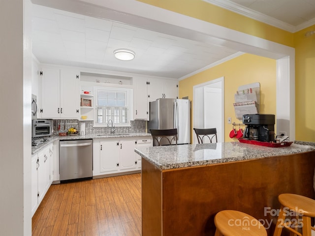 409 E 18th St, Kannapolis, NC 28083 - kitchen with appliances with stainless steel finishes, a peninsula, a kitchen bar, decorative backsplash, and open shelves