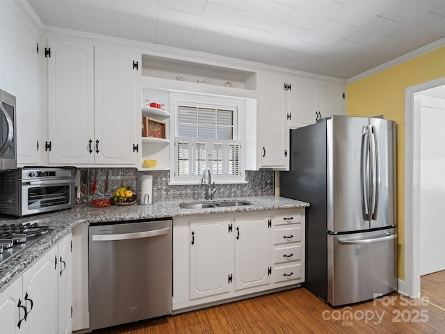 409 E 18th St, Kannapolis, NC 28083 - kitchen featuring appliances with stainless steel finishes, white cabinetry, decorative backsplash, light wood-style flooring, and ornamental molding