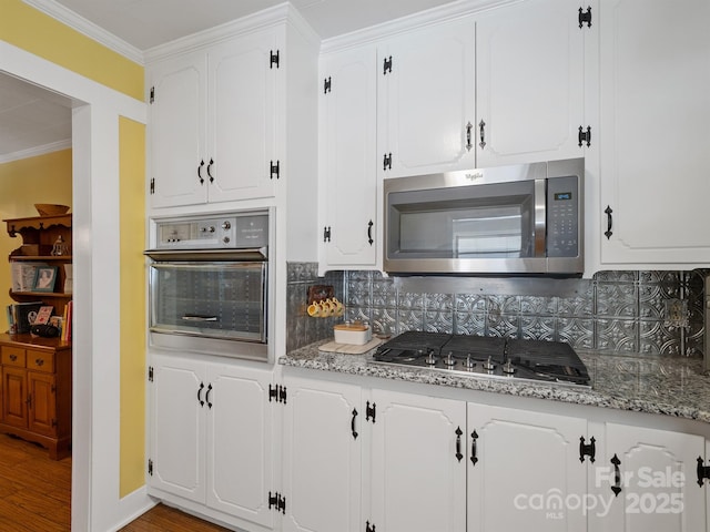 409 E 18th St, Kannapolis, NC 28083 - kitchen with appliances with stainless steel finishes, decorative backsplash, white cabinets, ornamental molding, and wood finished floors