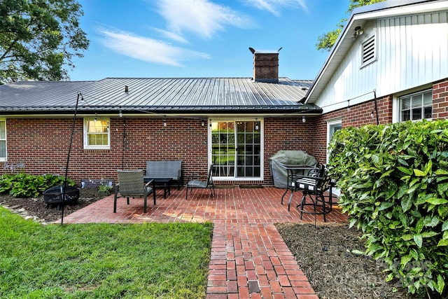601 Pennell St NE, Lenoir, NC 28645 - rear view of property featuring a chimney, brick siding, a patio area, a metal roof, and a yard