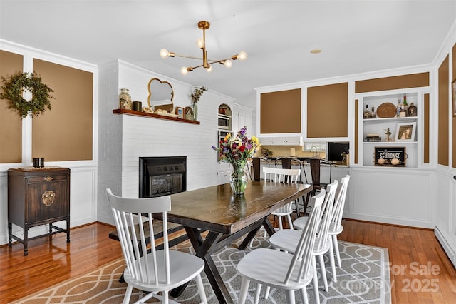 601 Pennell St NE, Lenoir, NC 28645 - dining space with light wood-type flooring, a chandelier, a fireplace, crown molding, and a decorative wall