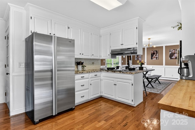 601 Pennell St NE, Lenoir, NC 28645 - kitchen featuring appliances with stainless steel finishes, under cabinet range hood, light wood-type flooring, a peninsula, and white cabinets